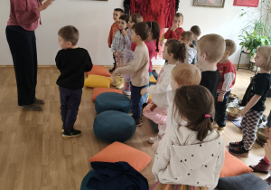 Dzieci stoją przy kolorowych pufach.