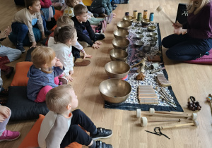 Dzieci siedzą przy metalowych misach.