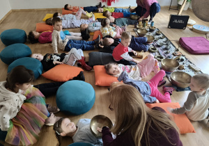 Pani prowadząca warsztaty kładzie misę na brzuchu dziecka.