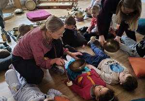 Prowadząca warsztaty uderza drewnianą pałką w metalową misę.