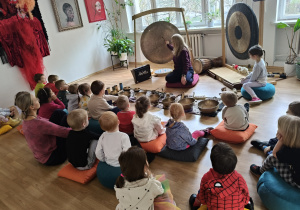 Dzieci siedzą podczas warsztatów na kolorowych misach.