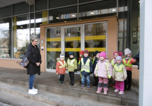 Grupa dzieci stoi przy budynku.