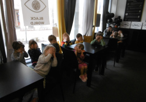 Grupa dzieci siedzi w sali.