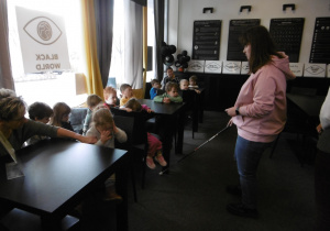 Osoba prowadząca warsztaty pokazuje dzieciom laskę dla osób niewidomych.