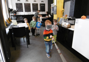 Chłopiec trzyma laskę i idzie przez salę.