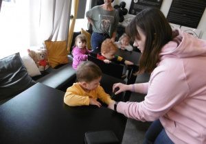 Pani prowadząca warsztaty dotyka ręki chłopca.