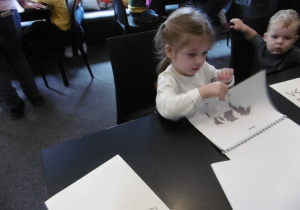 Dziewczynka trzyma w ręku kartkę z ilustracją.