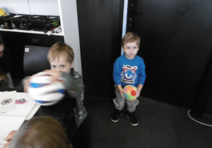 Chłopiec stoi i trzyma w ręku piłkę.