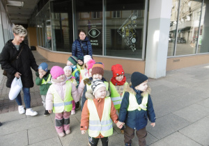 Grupa dzieci stoi przed budynkiem.