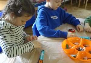 Dwoje dzieci siedzi przy stoliku.