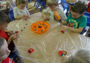 Dzieci siedzą przy stoliku i wykonują zadanie.