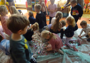 Dzieci zbierają kolorowe kulki.