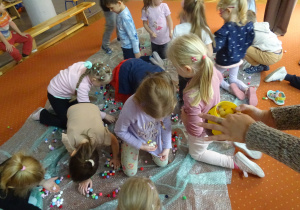 Dzieci zbierają kolorowe kulki.