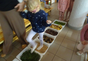 Inna dziewczynka idzie drogą zbudowaną z róznych materiałów.