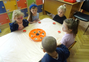 Dzieci siedzą przy stole pokrytym folią.