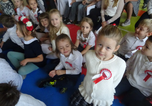 Dzieci siedzą na materacach na sali gimnastycznej.