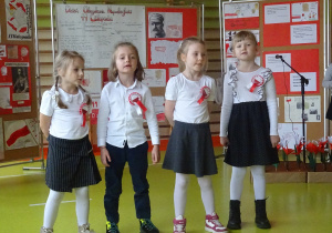 Czwórka dzieci stoi na środku i wykonuje pieśń patriotyczną.
