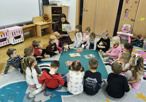 Dzieci siedzą w kole i oglądają zdjęcie jeża.