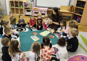 Dzieci siedzą w kole i trzymają złożone ręce.