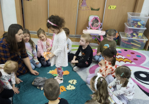 Dziewczynka stoi na środku koła przy nauczycielce.