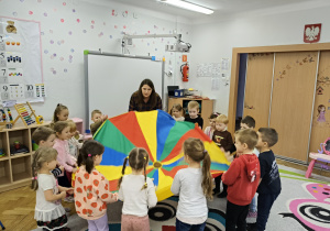 Dzieci bawią się wspólnie kolorową chustą.