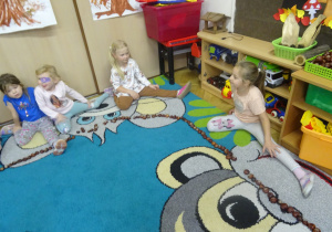 Dzieci siedzą w półkolu.