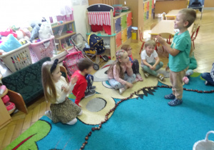 Chłopiec stoi przed dziećmi.