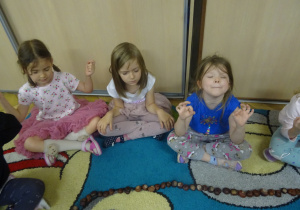 Trzy dziewczynki siedzą obok siebie.