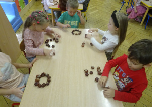 Dzieci układają kasztany na stole.