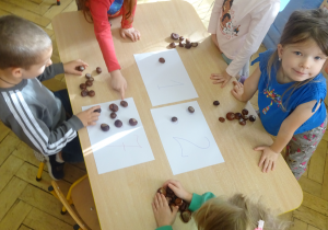 Inna grupa dzieci stoi przy stole.