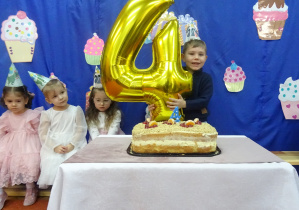 Chłopiec stoi obok cyfry cztery.