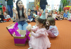 Dzieci siedzą na dywanie i wspólnie śpiewają piosenkę.