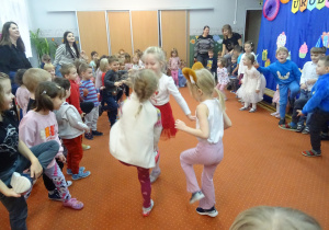 Troje dzieci tanczy wspólnie w kole.