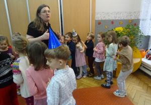 Nauczyciel stoi po środku dzieci i współnie tańczy z dziećmi.