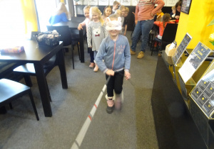 Dziewczynka idzie trzymając przed sobą laskę.