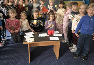 Dzieci stoją wokół stolika.