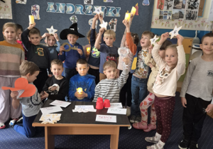 Dzieci podnoszą wysoko ręce do góry z zapalonymi lampkami.