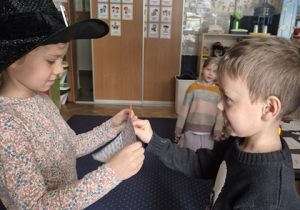 Chłopiec przekuwa szpilką kartkę.