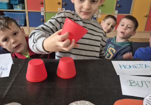 Chłopiec trzyma czerwony plastikowy kubeczek.