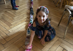 Dziewczynka kładzie swój but przy butach innych dzieci.