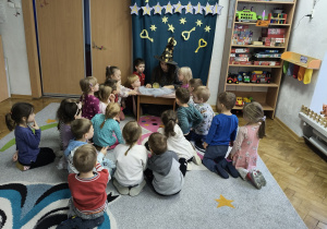 Dzieci siedzą na dywanie.