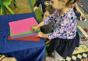 Dziewczynka wyjmuje kolorowe karki leżące na stoliku.