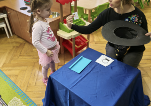 Dziewczynka stoi przy nauczycielce przebranej za wróżkę.