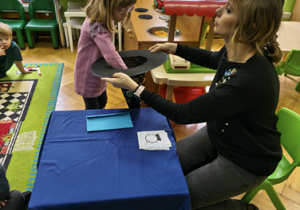 Dziewczynka wyjmuje wróżbę z kapelusza.