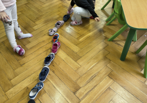 Dzieci układają buty jedno za drugim.