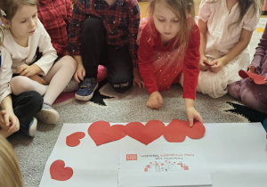 Dzieci naklejają papierowe serduszka.