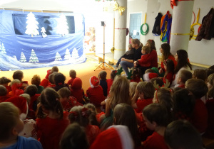 Dzieci siedzą na dywanie podczas oglądania spektaklu.