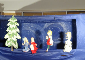 Lalki i choinka stoją na scenie.