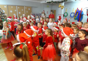 Grupa dzieci tańczy przy Mikołaju.