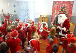 Dzieci wspólnie tańczą z osobą przebraną na Elfa i z Mikołajem.